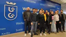 Zdjęcie partnerów projektu SAFER na tle granatowej ściany z białym sygnetem UG i powitaniami w różnych językach