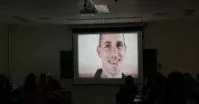 Widok zaciemnionej sali ćwiczeniowej, w której odbywa się projekcja filmu Prison Movie - szeroki kadr