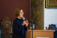 Kobieta przemawia za mównicą trzymając mikrofon