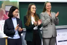 rzy uśmiechnięte młode kobiety, laureatki konkursu (Anna Grabowska, Anna Kulma i Agata Myszka), stoją obok siebie i klaszczą w dłonie na tle zielonej tablicy.