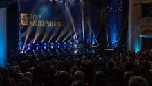 Zdjęcie z gali nauki polskiej, na śordku sceny stoi konferancjer w garniturze
