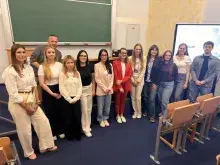 Zdjęcie przedstawiające osoby stojące przed pełną aulą na rozstrzygnięciu konkursu.
